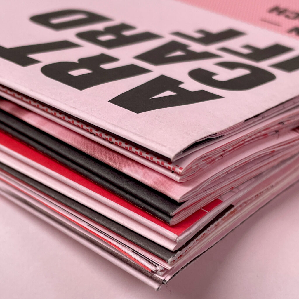 A stack of pink-paper leaflets with ARTCARDIFF on the cover.